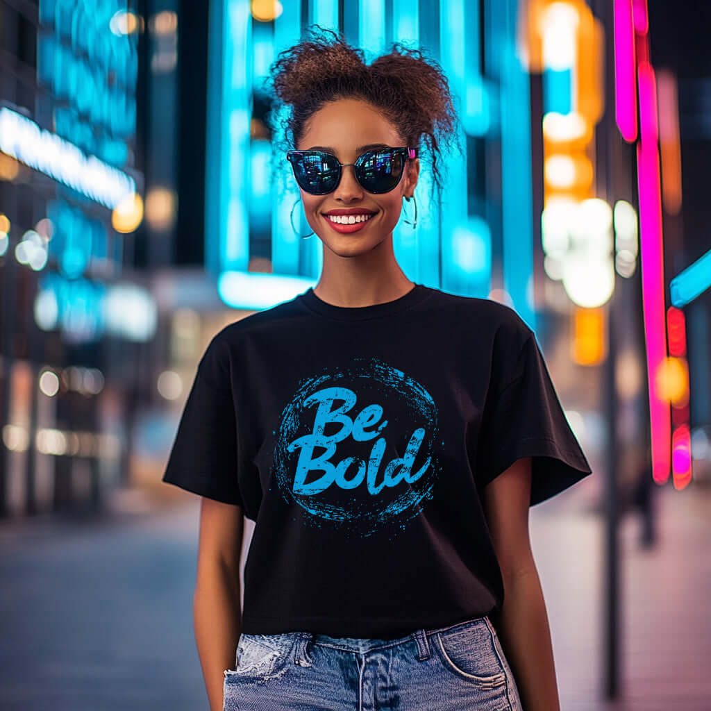 Confident man wearing Be Bold unisex black t-shirt in a vibrant city setting, showcasing a modern and empowering style.